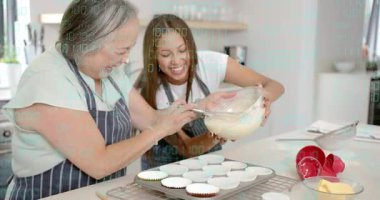 Genç kızlar kaseyi eğiyor, ebeveynler spatulayı kazıyor, dolgu malzemelerini fırında pişirmek için döküyorlar. Kekler, hamur işleri, mutfak, aile, takım çalışması, samimiyet, yaşam tarzı