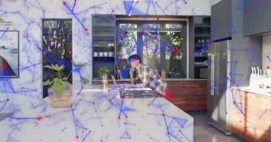 Mutfakta dizüstü bilgisayar kullanan bir adam var. Uzak verileri gösteren bir ağ kaplamasına neden oluyor. Ada, birey, arıza, dijital, tele çalışma, güneş ışığı, konut