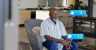 Son sınıf öğrencisi koltuğunda oturmuş sosyal medya uyarıları alıyor. Yörüngedeki baloncuklar erişebildiğini gösteriyor. Bildirimler, koltuk, ev, yaşlı, modern, dekor, gülümseme