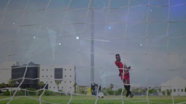 Kırmızı forvet sayı yapmak için topa vuruyor, karanlık kalecinin dalışına ve kurtarışına neden oluyor, spor süpürüyor. Gol, ileri, kaydetme, işaret fişeği, gündüz, zift, çim