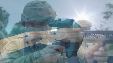 Öncü asker karabina kaldırıyor ve savunma tatbikatında optik hizaya geliyor. Çerçevenin üzerinde dalgalanan bayrak var. Taktik, eğitim, açık hava, kamuflaj, miğfer, tüfek, optik