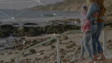 Kadın havuzu görmek için merdivenlerden iniyor, erkek sabit duruyor, teknoloji kaplaması taşıyıcı güvenliğini gösteriyor. Aile, sahil, kıyı şeridi, gelgit, kaya, bebek, bebek