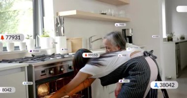 Kızı fırına uzanıyor, yüzen rozetlere sebep oluyor, annesi kapıyı tutarken ikisi de fırını inceliyor. Mutfak, ikili, işbirliği, modern, parlak, sağlıklı, fırın üstü