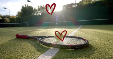 Alçak güneş parlaması, tenis topunun raket tellerini kaldırması romantizmi çağrıştırırken yükselen kalpler yaratıyor. Yakın çekim, açık hava, mahkeme, ağ, çit, ışıklar, işaret fişeği