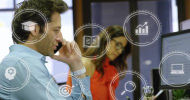 Mavi gömlekli konuşan adam telefonu monitörlerle, simgelerle, kopyalama alanıyla paylaşıyor. Ofis, çalışma alanı, işbirliği, iş arkadaşları, analitik, kodlama, teknoloji