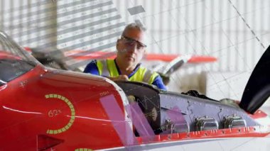 Havacılık göstergeleri motoru kaplarken, teknik olarak dipstick denetim motoru yerleştiriliyor. Tamirci, bakım, uçak, hangar, pervane, teşhis, çizelge