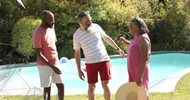 Havuz başında konuşan üç yetişkin, sakallı bir adam kadının omzuna dokunuyor, eğlence için selamlama başlatıyorlar. Üçlü, açık hava, samimi, stok, arka bahçe, güneşli, şapka