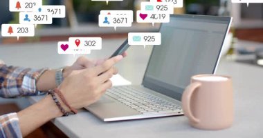 Akıllı telefonu dizüstü bilgisayardan dinleyen adam pazarlama için yüzen metrik bulut kalabalığı masası yaratıyor. Uzaktan kumanda, nişan, bildirimler, dağınıklık, çalışma alanı, kupa, ekose