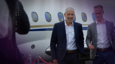 Olgun bir adam kırmızı halatı geçerek bir jet jesti yaparak iş dünyasının gelişini ön plana çıkarıyor. Uçak, VIP, yöneticiler, asfalt, fotoğrafçı, siluet, bulutlu