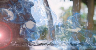 Dalgalı mavi su girdapları ağaçların yakınındaki sığ havuzda yansımalar yaratıyor. Yarı saydam, soyut, yansıtıcı, bokeh, açık hava, ağaçlık, damlacıklar