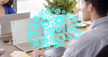 Tasarımcı stilus 'u tablet üzerinde tıkırdatarak aygıtların yol gösterici dizaynının üzerinde yüzen deniz mavisi dişlilerine neden oluyor. Yaratıcı, profesyonel, gündüz, ofis, dişli, dizüstü bilgisayar, fabrika