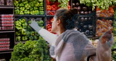 Alışveriş yapan kişi markette yeşil biber arıyor ve kontrol ederken İHD 'nin yükselmesine neden oluyor. Üretim, pazar, koridor, teftiş, taze, renkli, dijital