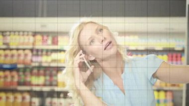 Telefon tutan ve market alışverişini kıyaslayan bir kadın. Artan grafikleri işaretleyen bir telefon görüşmesi. Süpermarket, alışveriş, akıllı telefon, koridor, ürün, fiyatlandırma, perakende
