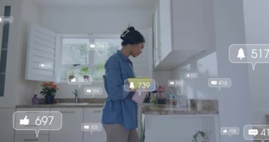 Temizlik sırasında tezgahı spreyleyen ve silen bir kadın, etrafında sosyal bildiriler yükseliyor. Mutfak, gün ışığı, eldivenler, sprey, sünger, bulaşıklar, pencere.