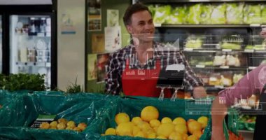 Market çalışanları narenciye düzenlerken bir kadın da konteynırların üzerinde yüksek çözünürlük olduğunu göstererek borsa güncellemesi yapıyor. Üretim, işbirliği, perakende, üst üste, animasyon, pazar, yoldaşlık