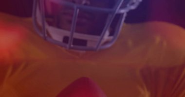 Futbolcu topu tutuyor, kamera yukarı hareket ediyor, renkli fişekler spor reklamı için odaklanmış bakışları ortaya çıkarıyor. Sporcu, dramatik, sinematik, mercek, mor, turuncu, stüdyo