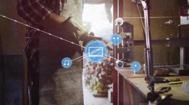 Zanaatkar aletlere uzanıyor, ahşabı bitirirken mavi simgeler ve çizgiler ellerinden fışkırıyor. Esnaf, marangoz, atölye, tezgah, kereste, makine, arka ışıklandırma