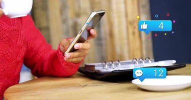 Woman tapping phone at table, checking social media, alerts rising to double digits, sipping mug. Smartphone, notifications, multitask, cafe, cozy, planner, glasses