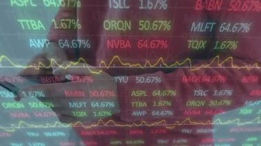 Adam vurma cihazı, finans saatlerini gösteren yansıma ve sarı grafik güncellemesi, takip pazarı. Akıllı telefon, eller, ofis, veri, etkileşim, iş, şirket