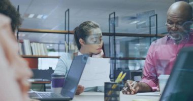 Ofisteki kadın kağıtları incelerken kıdemli adam notları tıkırdatıyor ve masanın üstünde veri örtüsü oluşturuyor. Takım çalışması, işbirliği, toplantı, açılış planı, dizüstü bilgisayarlar, belgeler, görselleştirme