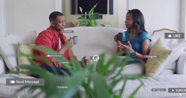 Kadın konuşurken ve el kol hareketi yaparken, erkek kupa tutarken, yüzler üzerinde sosyal beğeni gösteren rozetler oluştururken. Çift, sohbet, ev, kanepe, bitki, üst üste, etkileşim