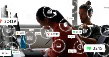 Kadın yazma, ofis alarmları için bilgisayara taşınma, erkek iş arkadaşı otururken, ikonlar çoğalırken. İşbirliği, meslektaşlar, iş akışı, bildirimler, verimlilik, arka ışıklandırma, çalışma alanı