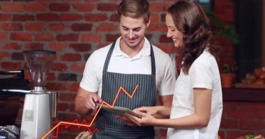 Kahveci tıkırtısı tableti ve kafede elinde tablet olan meslektaşı, satışları takip eden çizgi grafikleri canlandırıyor. Takım çalışması, işbirliği, analitik, gösterge paneli, konukseverlik, espresso, fırın