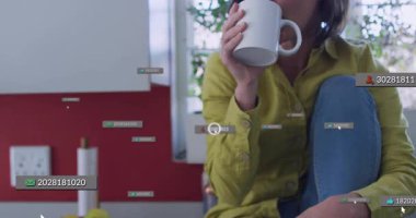 Tezgahta bardak tutan bir kadın, sol veri etiketleri yükseliyor. Ellerin yanında teknolojik UI kümelerine sebep oluyor, yansıtıyor. Bardak, kahve, mutfak, tefekkür, doğal, hafif, minimalist