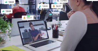 Kadın dizüstü bilgisayar seyrederken, erkek çizelgeleri işaret ediyor, rozetleri masanın üstünde yüzüyor, iş eğilimlerini gösteriyor. İzleyici, webinar, canlı yayın, uzaktan kumanda, ofis, birlikte çalışma, eşleştirme