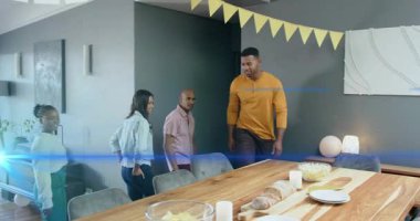 Başroldeki adam sandalyeyi çeker ve grubu ahşap yemek masasına götürür, aile yemeği için koltuk ayarlar. Toplanma, arkadaşlar, ev, rahat, modern, bunting, mumlar