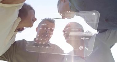 Kameraya yaslanmış dört yetişkin, AR takvimi görünür ve güncellenir Mart emirlerini onaylarken. Grup, arkadaşlar, açık hava, artırılmış gerçeklik, arayüz, işbirliği