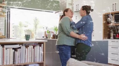 Mutfakta birbirine sarılan iki kadın, bağlantı teknolojisini gösteren animasyonlu ağ örtüşmesi. Çift, şefkat, samimiyet, gün ışığı, rahat, doğal, sıcak