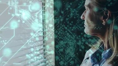 Kıdemli doktor panjurlara bakıyor, bakışlarını değiştiriyor, tableti kaldırıyor, klinik verileri deniz mavisi ile örtüyor. Hekim, ofis, ekran, veri, analitik, devre, dijital