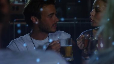 Kadın konuşuyor ve bardakları işaret ediyor. Adam dinliyor. Muhabbet eden mavi bokeh barın üzerinde yüzüyor. Çift, sohbet, göz teması, ortam, kabin, bokeh, gece hayatı.