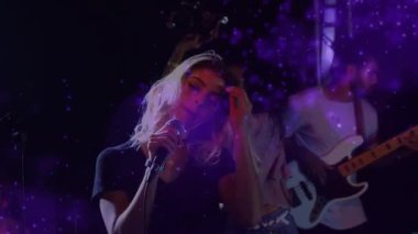 Baş vokalistin baş aşağı mikrofona inmesi, grup şarkı söylerken saçlarının sallanmasına, sahnede mor bokeh 'e neden oluyor. Şarkıcı, livemusik, ışıklandırma, hareket, enerji, topluluk, konser