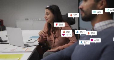 Buluşmada el kol hareketi yapan bir kadın dizüstü bilgisayarın etrafında sosyal rozetlerin yükselmesine neden oluyor. Ofis, işbirliği, iş arkadaşları, bildirimler, simgeler, belgeler, sunum