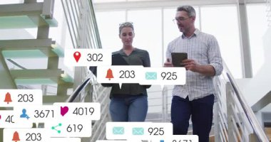 İş arkadaşları ofis merdivenlerinden iniyor, klasörü ve tableti kontrol ediyor, dokümanlarda büyüyen uyarıları izliyorlar. İşbirliği, takım çalışması, bildirim, gün ışığı, avlu, cam, iç mekan