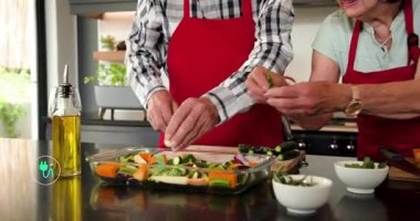 Kabak doğrayan yaşlı çift yemek pişirirken yüzen eko ikonlara neden oluyor, bitki ve yağ ekliyorlar. Mutfak, üretim, baharat, önlük, şarap, cam, çiseleme