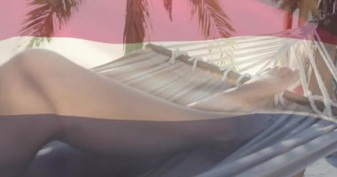 Kumsalda hamakta yatan bir kadın, dinlenmek için bacakları kayıyor. Avuç içi üst üste binerek seyahat ediyor. Uzuv, şekil, kum, ip, yaşam tarzı, tatil, stok