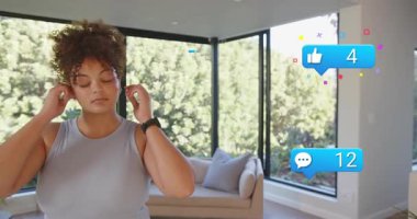 Yaratıcı, kulaklıkları ayarlayarak boyun-kol esneme hareketleri yaparak yukarıdan yükselen mavi sayaçları akıtmaya hazırlanıyor. Kadın, oturma odası, güneş ışığı, rahatlama, spor, minimalist, dinginlik.