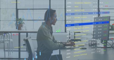 Açık ofisteki masaüstü bilgisayarını kullanarak açık tişörtlü orta yaşlı bir adam gibi çalışmak. Finans, analitik, gösterge paneli, grafikler, stok, saat, monitör