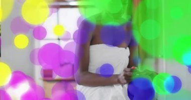 Kadın şişeyi kaldırıyor, güzellik bakımı için ellere losyon sürerken renkli daireler çiziyor. Bencillik, kaplıca, cilt bakımı, kibir, pencere ışığı, ışıltı, parmaklar