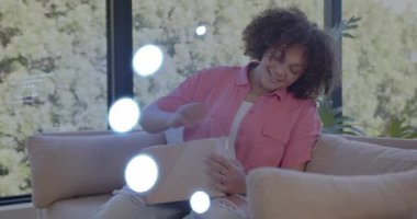 Kanepe degistirme kutusunda oturan, bant soyan, kutuyu açan ve dış ticaret alışverişini denetleyen bir kadin. Kutu açma, paket açma, ortaya çıkarma, keyif, merak, gün ışığı