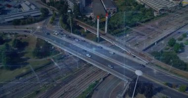 İHA kamerası eğik taramaya başlıyor. Çapraz üstgeçit, raylardan geçen arabaları takip etmek için taşıyor. Köprü, hava, kentsel, çok yönlü, trafik, araçlar, demiryolu