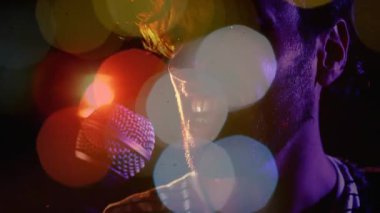 Erkek şarkıcı, müzik seti sırasında mikrofona şarkı söylüyor. Renkli Bokeh suratlı. Sahne, kulüp, spot ışıkları, mikrofon, vokal, performans, mercek