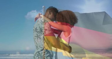 Alnını kucaklayan bir çift plaj meltemine dokunuyor. Pazarlama için bayrak örtüyor. Aşk, sarılma, deniz kenarı, güneş ışığı, ufuk, deniz, nazik