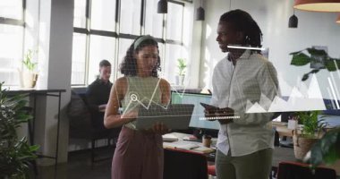 Kadın dizüstü bilgisayarı gösteriyor ve adam tablet tutuyor. İş verilerini genişletilmiş çizelgelerle gözden geçiriyor. Birlikte çalışma, işbirliği, takım çalışması, iş arkadaşları, ofis, grafikler, görselleştirme