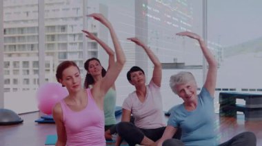 Eğitmende dört kadının ısınma turu için paspaslara uzanması, çizelge izleme formunu örtüyor. Grup, stüdyo, yoga, şehir manzarası, denge, gün ışığı, koordinasyon