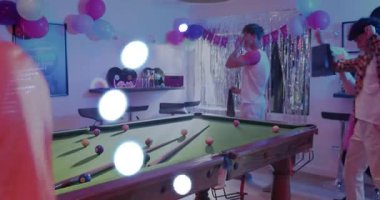 Grup, ellerinde hediyeler ve tabaklar ile bilardo masasından canlı parti ışıklarıyla geçiyorlar. Bilardo, balon, disko, replik, kutlama, olay, dekor