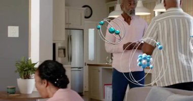 Yetişkin bir kadın elini uzatıyor, evde yaşlı bir kadının bileğine bakıyor, atomu sağlığını ön plana çıkarıyor. Bakım, aile, sıcaklık, empati, birliktelik, mutfak, kanepe.